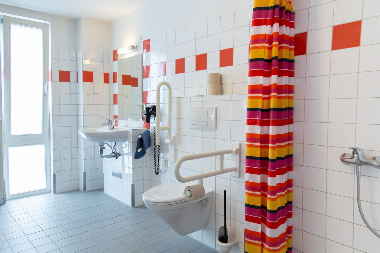 Rollstuhlfreundliches Badezimmer im Zweibettzimmer mit bodengleicher Dusche und Tageslicht