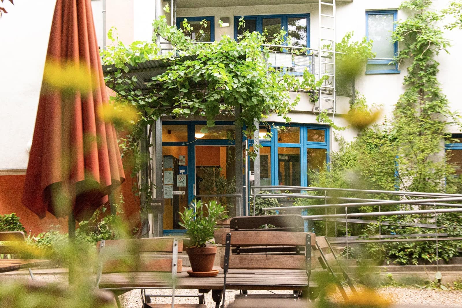 Tisch mit Sonnenschirm vor dem Eingang zum Biergarten